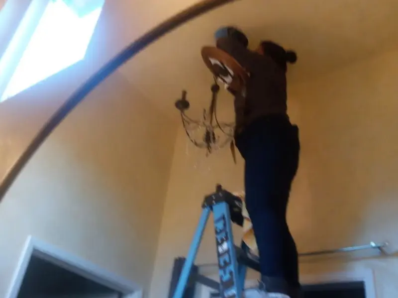 Electrician installing a chandelier in a Wind Lake residence